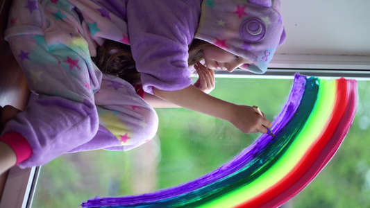 穿着睡衣的女学生在家里窗户上画彩虹留在家中闪光暴徒视频