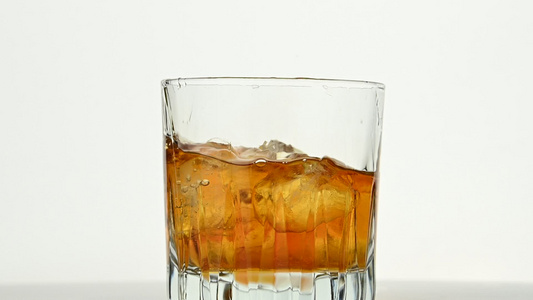 冰雪的立方体倒在威士忌杯中而不是白色视频