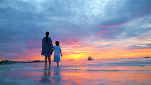小女孩和快乐的母亲在海滩美丽的夕阳中剪影地平线上的10秒视频