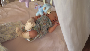 婴儿有打嗝躺在婴儿床与玩具移动28秒视频