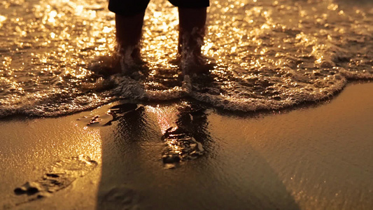 在海滩的金色沙滩上海日落波溅起婴儿脚的特写蹒跚学步视频