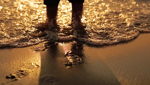在海滩的金色沙滩上海日落波溅起婴儿脚的特写蹒跚学步24秒视频