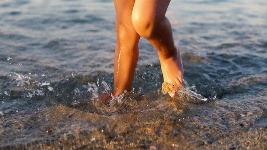 赤脚小婴儿走得很快日落时在浅海水中喷洒视频