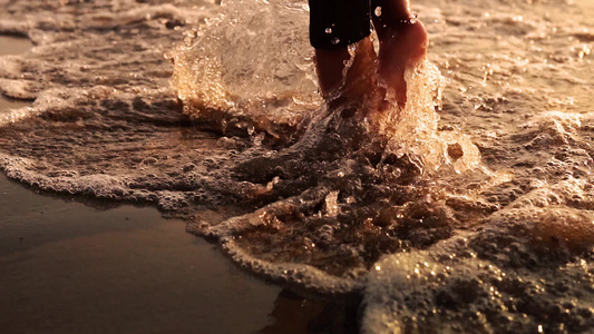 婴儿脚在沙滩上行走的电影拍摄在日落时以慢速运动冲浪视频