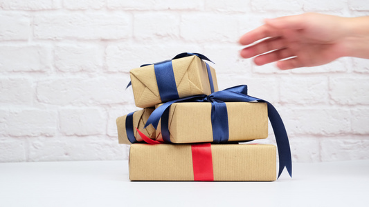 包裹在棕色纸上并绑有丝带的长方形礼品盒带有弓和白色视频