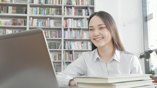 在图书馆使用笔记本电脑时迷人的亚洲女性在笑视频