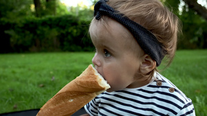 一个小可爱的女婴坐在花园的草坪上拿着新鲜的面包12秒视频