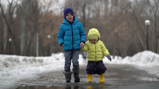 男孩和女孩在冬天走在水坑里视频