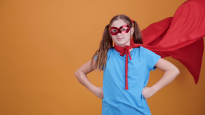 可爱的年轻女孩在橙色背景背景下扮演超级英雄12秒视频