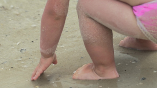 一个小孩在沙滩上水中冲浪慢动作视频