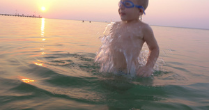 戴护目镜的小孩在日落时在海中玩得开心11秒视频