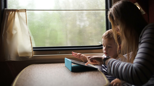 母亲和儿子在火车上的触摸板上玩游戏视频