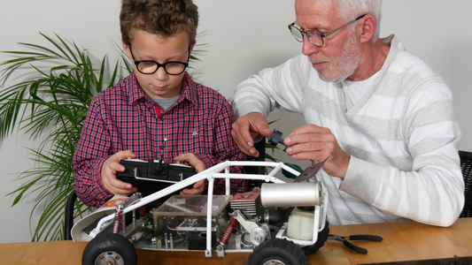爷爷和儿子小男孩在修理无线电控制车的模型视频