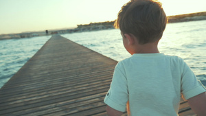 小男孩日落时在码头奔跑54秒视频