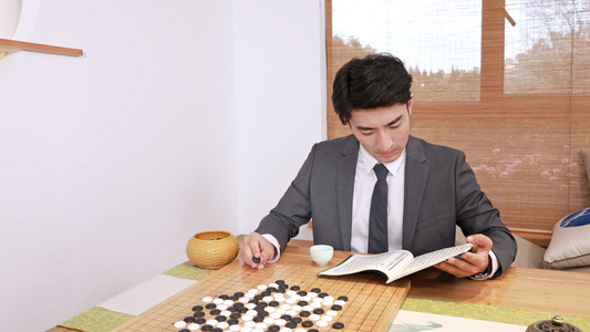 穿西装的男青年边喝茶边围棋书籍视频