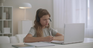 在线儿童在家上学女孩通过耳机和笔记本电脑上的视频聊天9秒视频