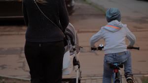 大男孩骑自行车在街上与母亲和婴儿在一起7秒视频