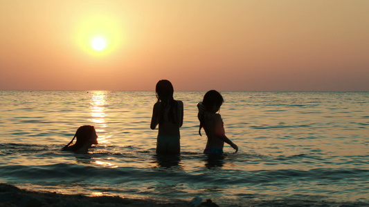 日落时女孩在海中玩球视频