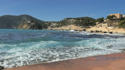 黑头发女人走在海边的岩石岸上挥舞着水在主要岛屿西班牙视频