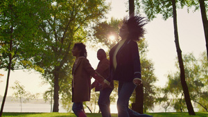 孩子牵着父母的手在绿色公园散步21秒视频
