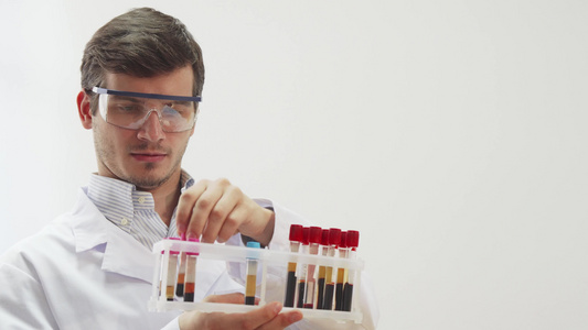 佩戴特别实验室眼镜的医生用血液检查试管;在检查时使用视频