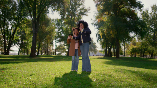 快乐的妈妈和站在公园里的可爱微笑的女儿在线通话视频