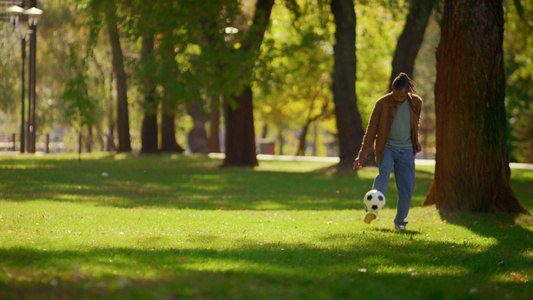 快乐的父亲独自在阳光明媚的公园踢足球视频