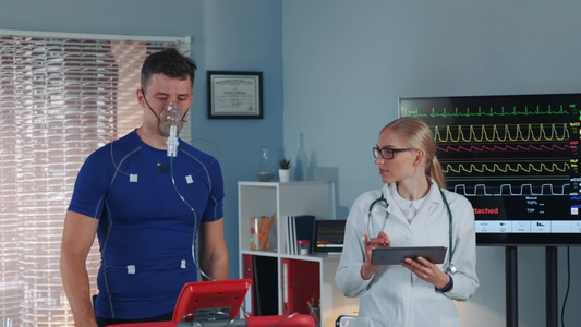 参加氧气面具运动运动员进行压力测试而心脏病学家则用视频