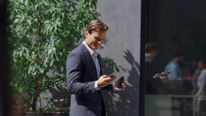 微笑着检查智能手机的财务人员走在外面的现代工作场所20秒视频