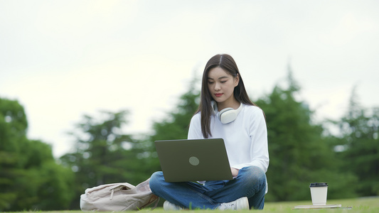 校园女生坐在草地上用电脑视频