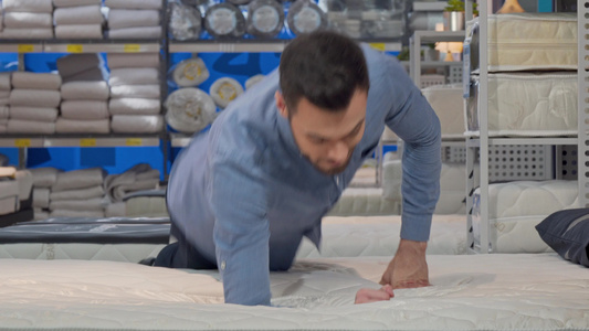 英俊男子选择整形床垫躺在店铺的新床上视频