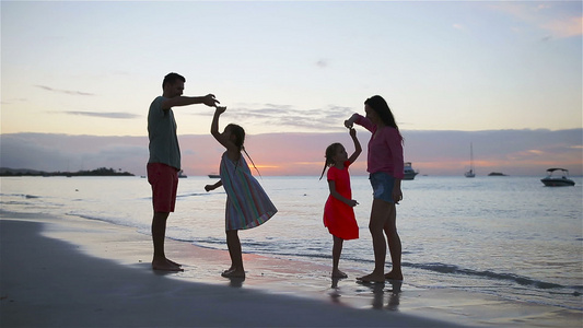 父母和两个孩子在日落的海滩上玩得很开心四人家庭相爱视频