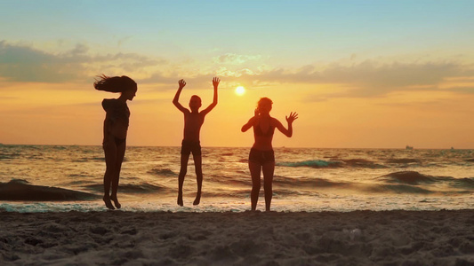 一群玩乐在日落的海滩上跳跃的孩子慢动作视频