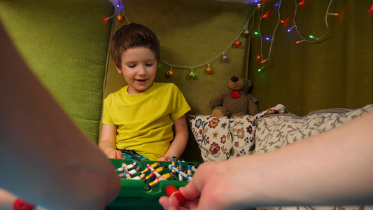 和孩子一起玩桌面游戏男孩在里面有枕头的小游戏室里和视频