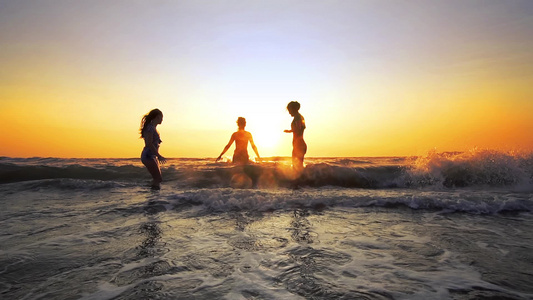 年轻女子在热带海滩以缓慢运动的方式在日落时跳舞和跳入视频