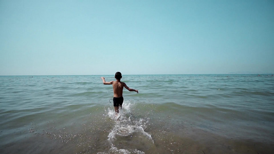 快乐的小男孩在水中奔流在海滩上玩海浪视频
