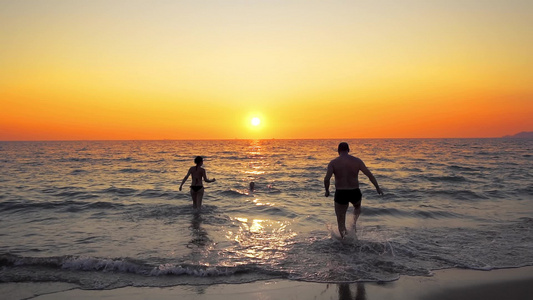 快乐的年轻家庭在日落时在海滩上奔跑愉快家庭旅行概念视频