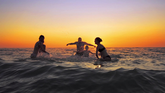 家庭成员在夏日海滩的日落时分欢快跳跃电影慢动作视频