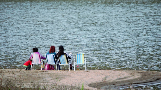 一家人坐在湖边的海岸上坐着椅子视频