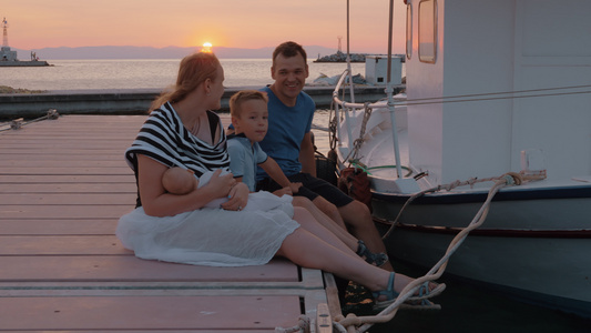 日落时父母双亲与大儿子和婴儿坐在码头上视频