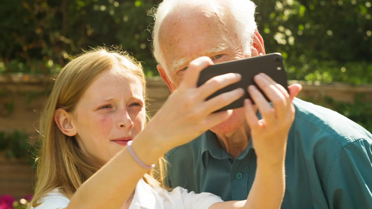 老人和他孙女用智能手机自拍自拍视频