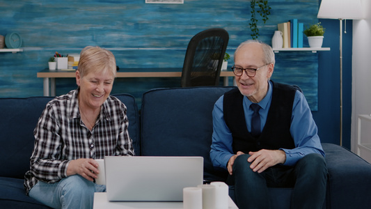 快乐的老年情侣在视频电话中与使用笔记本电脑的侄子挥手视频