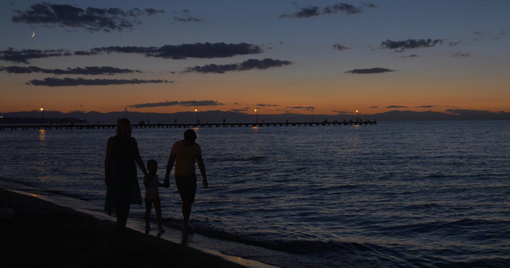 父母和子女在黄昏时在海中行走视频