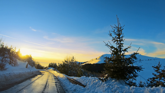 日落时冬林中雪覆盖道路上的山上驾驶小马视频