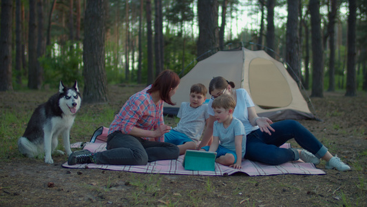 两个30多岁的母亲和两个儿子在夏季野营假期与森林帐篷视频