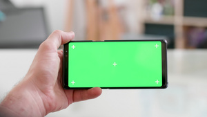 用绿色屏幕横向握着智能手机并用绿色屏幕17秒视频