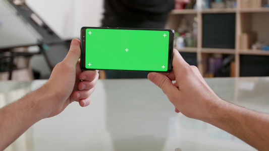 持有智能手机以绿色屏幕水平水平保持双向绿屏视频