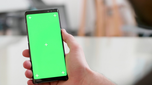 手持绿屏的智能手机近距离拍摄镜头视频