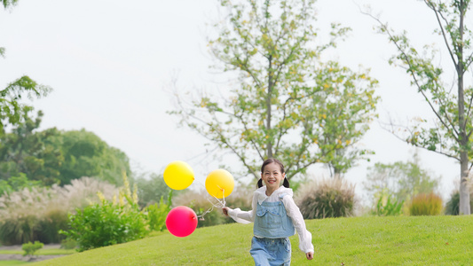 女孩在草地上举着气球开心跑视频