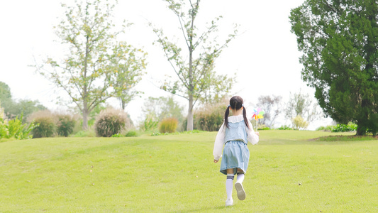 女孩在草地上玩纸风车开心跑视频
